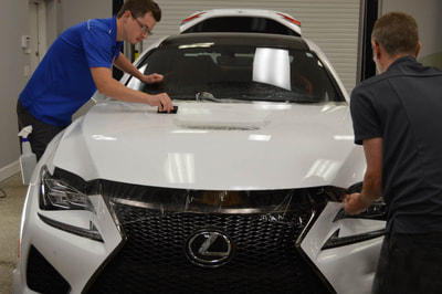 Lexus hood wrapped by two employees
